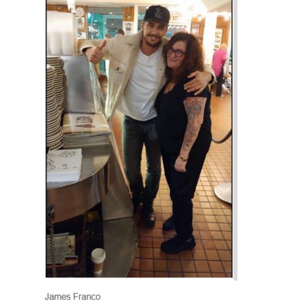 Actor James Franco with a woman at Canter's Deli, both smiling and posing for a photo.