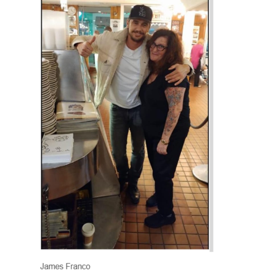 Actor James Franco with a woman at Canter's Deli, both smiling and posing for a photo.