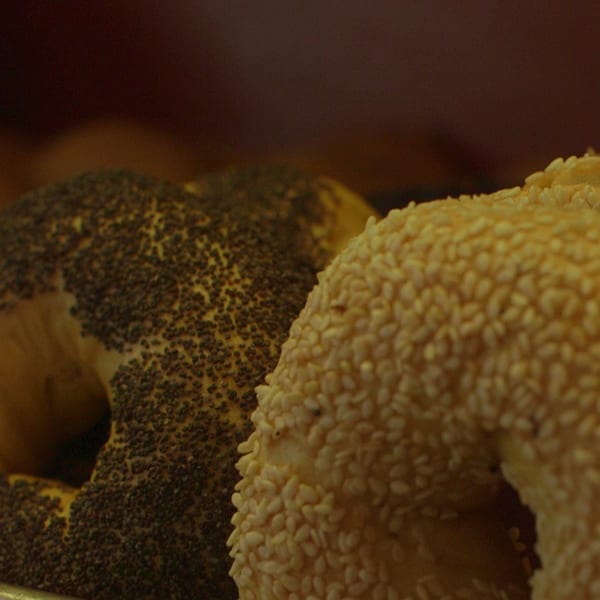 Close-up of two bagels, one covered in poppy seeds and the other in sesame seeds.