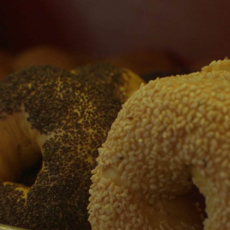 Close-up of two bagels, one covered in poppy seeds and the other in sesame seeds.
