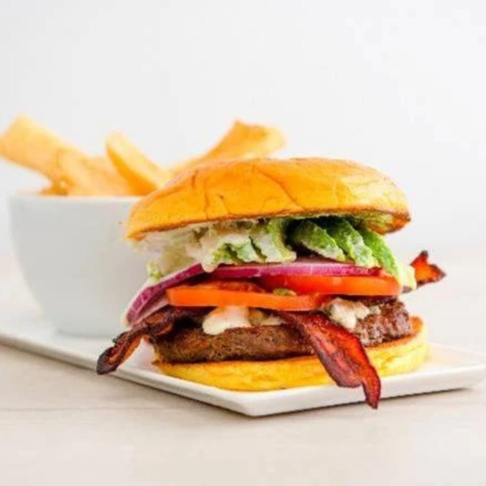 A Canter's Deli burger with bacon, lettuce, tomato, onion, and avocado, served with fries.