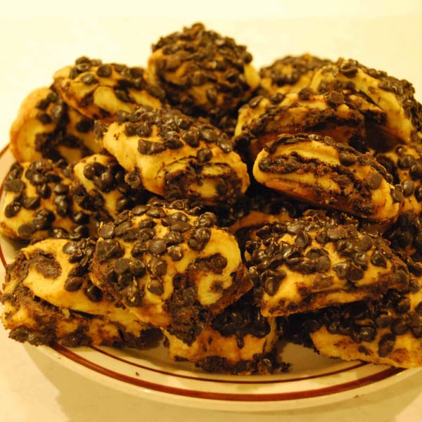 A plate piled high with Canter's Deli chocolate chip rugelach, showcasing their rich, dark chocolate filling.