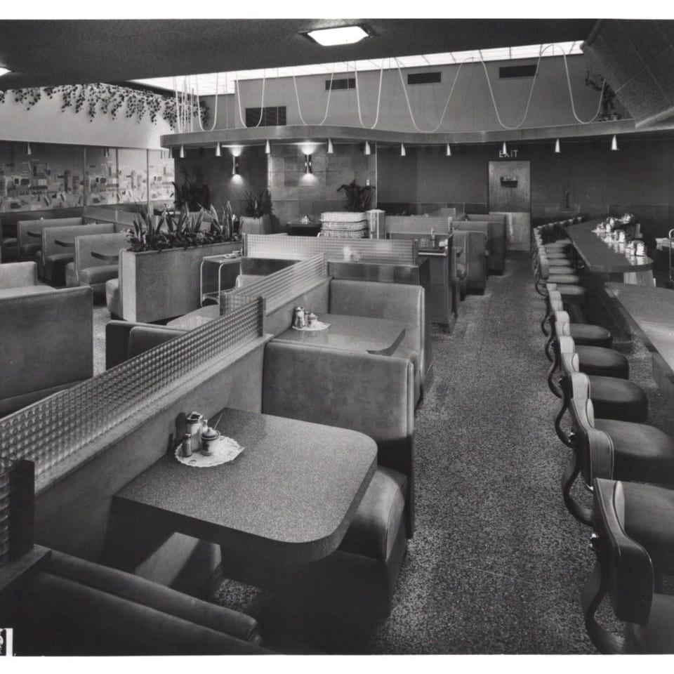 Black and white interior of Canter's Deli with booths, tables, and a long counter with stools.