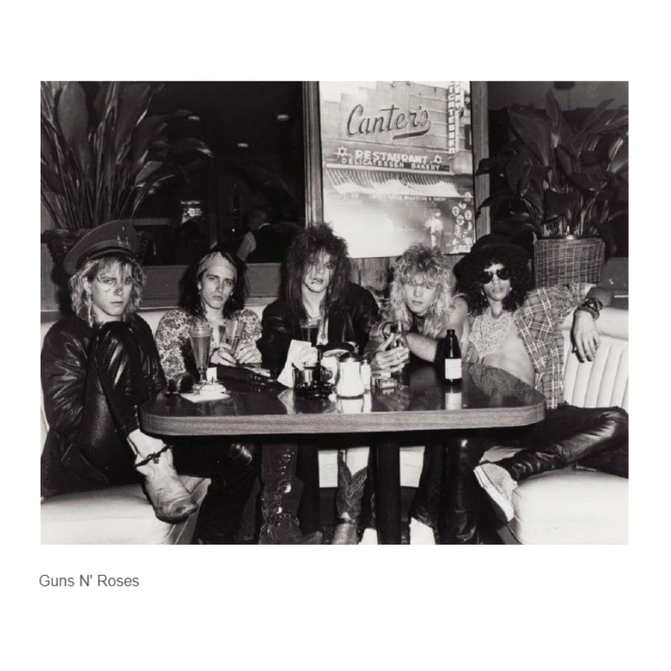 Guns N' Roses band members sitting at a table inside Canter's Deli, black and white.