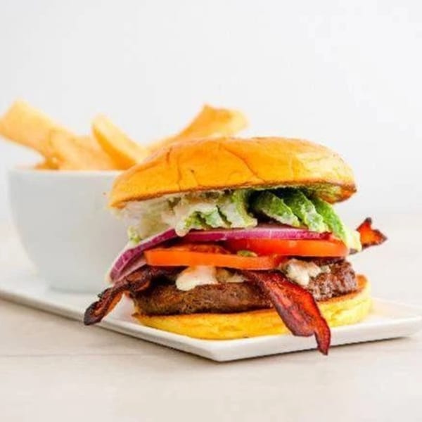 A Canter's Deli burger with bacon, lettuce, tomato, onion, and avocado, served with fries.