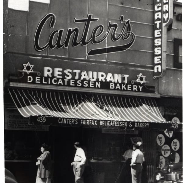 Black and white photo of Canter's Deli exterior with striped awning and people walking by.