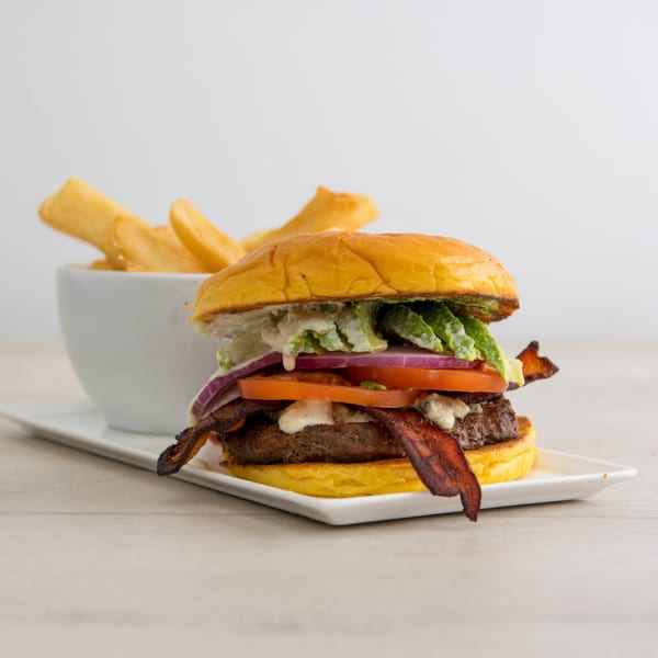 A Canter's Deli burger with bacon, avocado, tomato, onion, and lettuce, served with fries.