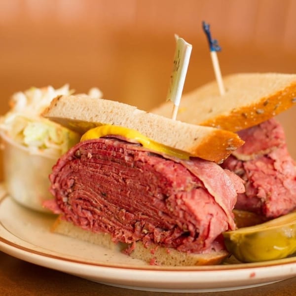 Canter's Deli pastrami sandwich on rye with mustard, coleslaw, and a pickle spear.