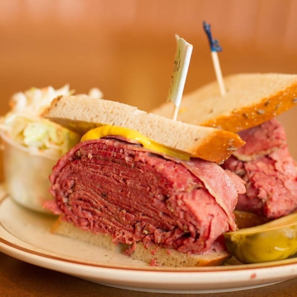 Canter's Deli pastrami sandwich on rye with mustard, coleslaw, and a pickle spear.