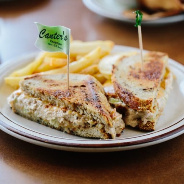 Canter's Deli tuna melt sandwich with a branded flag and french fries on a white plate.