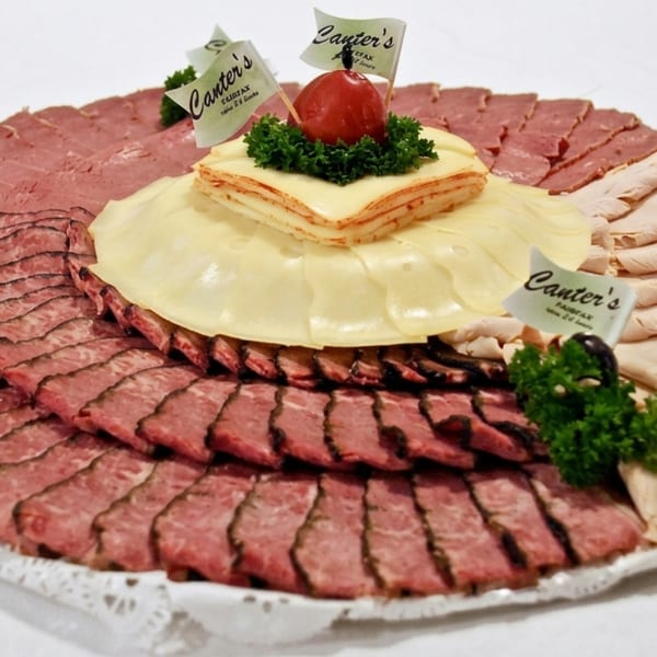 Canter's Deli meat and cheese platter with corned beef, turkey, Swiss cheese, and cherry garnish.