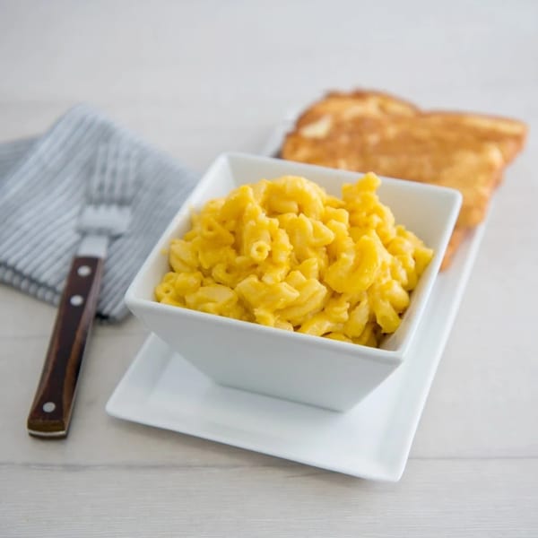 Canter's Deli macaroni and cheese in a white bowl with a side of toast and a fork.
