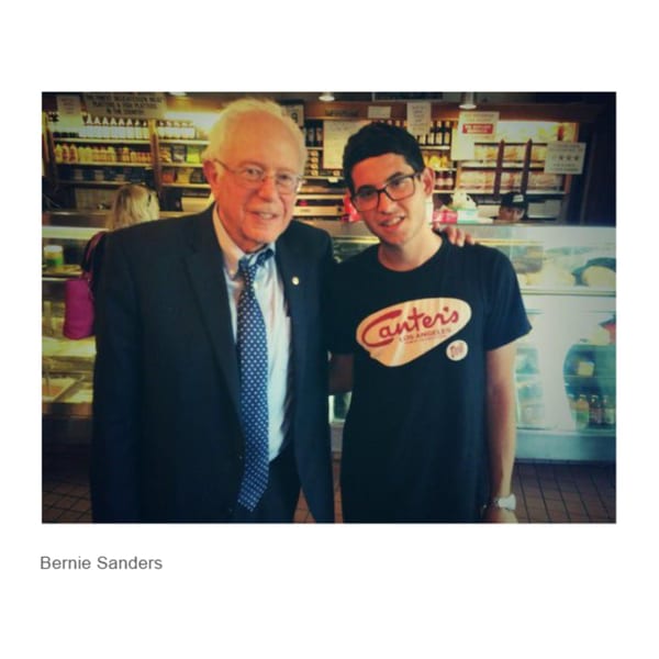 Bernie Sanders and a young man in a Canter's Deli t-shirt pose inside the deli.