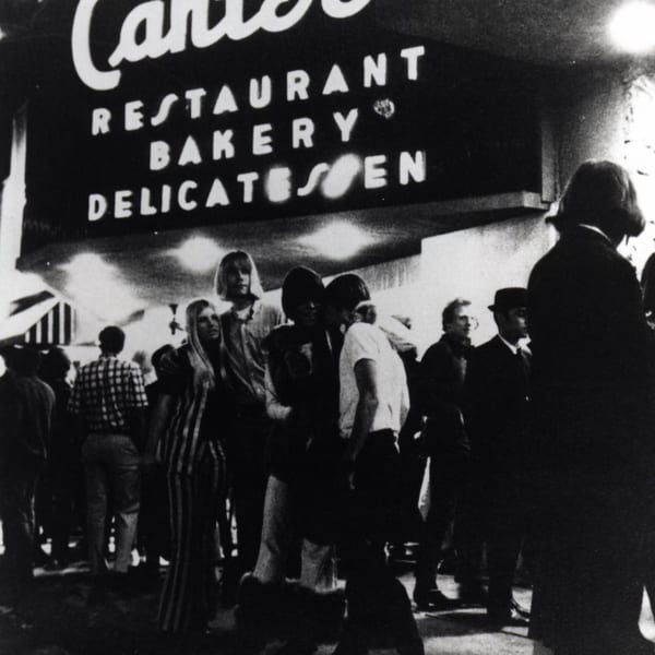 Black and white photo of a crowd of people gathered outside Canter's Deli at night.