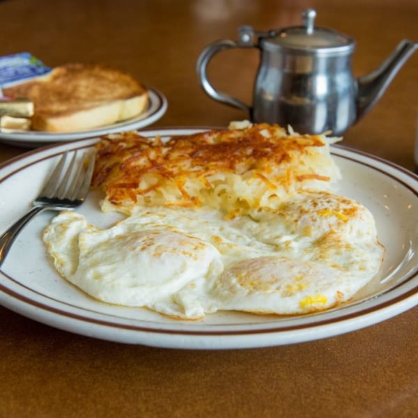 Canter's Deli breakfast with fried eggs, hash browns, toast, and a metal teapot.