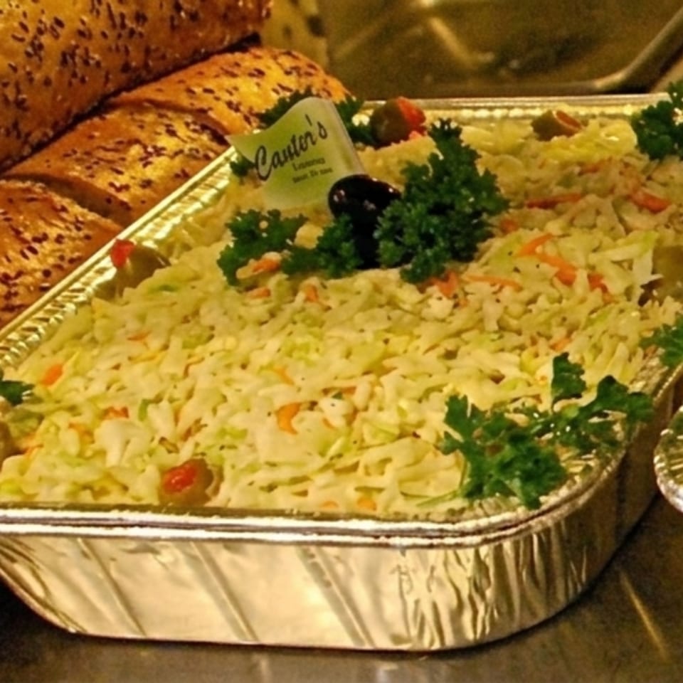 Canter's Deli coleslaw in a foil pan, garnished with parsley, olives, and pimentos.