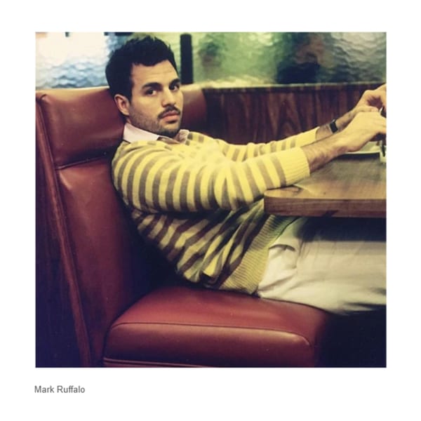 Mark Ruffalo sitting in a red booth at Canter's Deli, wearing a striped sweater.
