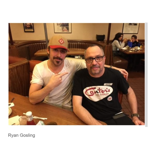 Ryan Gosling and a man in a Canter's Deli shirt pose for a photo in a restaurant booth.