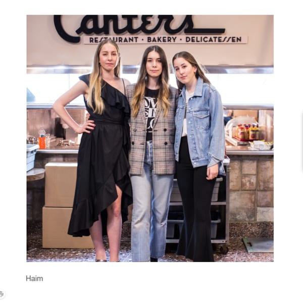 Three women posing in front of the Canter's Deli sign and counter area.