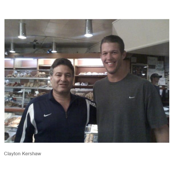 Two men, one identified as Clayton Kershaw, smiling in front of a deli display case.