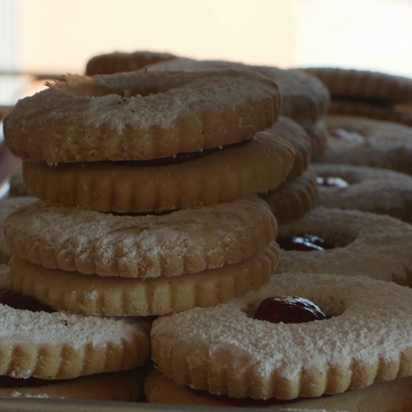 Stacked, powdered sugar-dusted Canter's Deli cookies with jam centers, ready to be enjoyed.