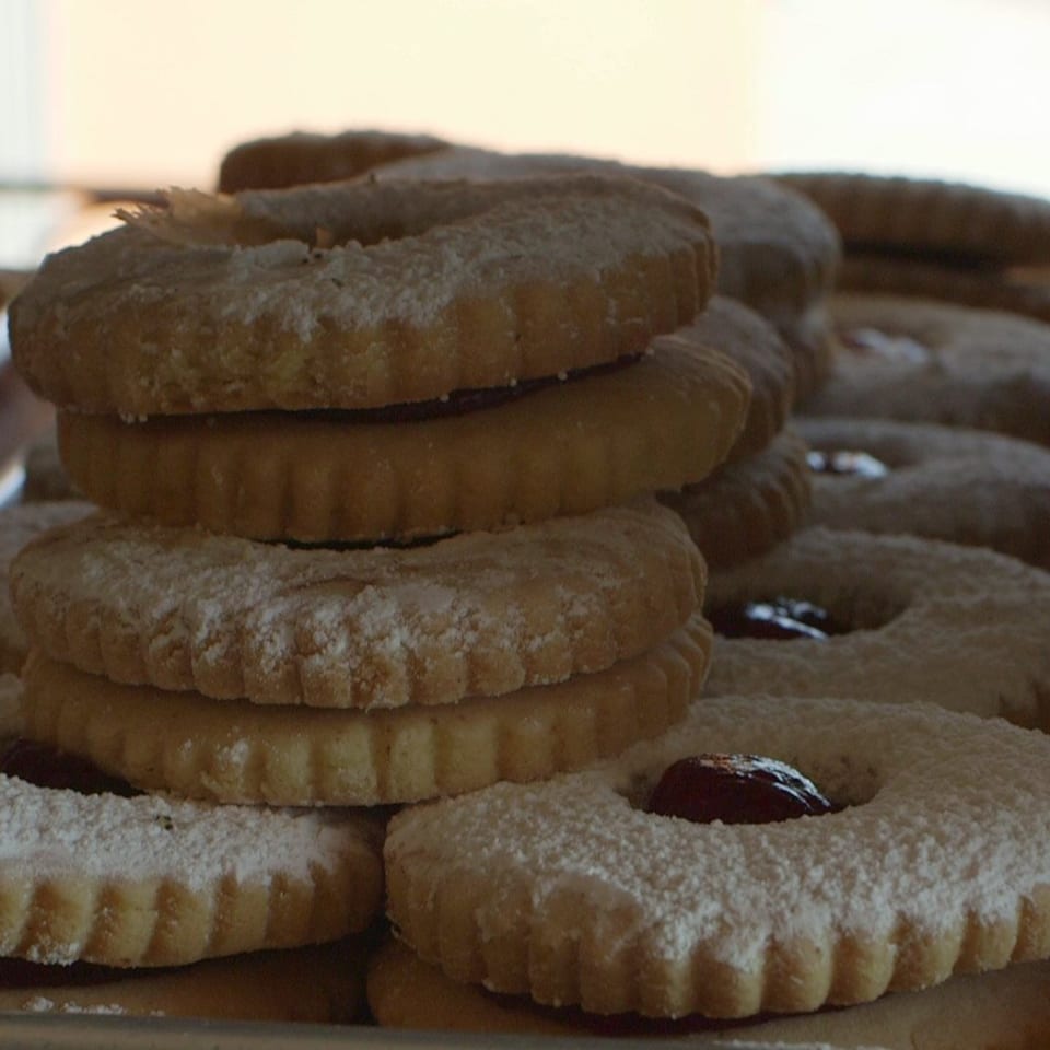 Stacked, powdered sugar-dusted Canter's Deli cookies with jam centers, ready to be enjoyed.
